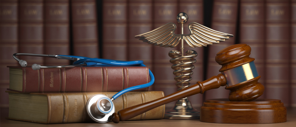 a stethoscope resting on a stack of books, next to the books are a caduceus and gavel